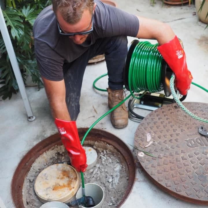 Plumber jetting a blocked drain outside a Melbourne home